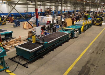 Large industrial workshop with conveyor belts and heavy machinery along a long, organized production line inside a factory.