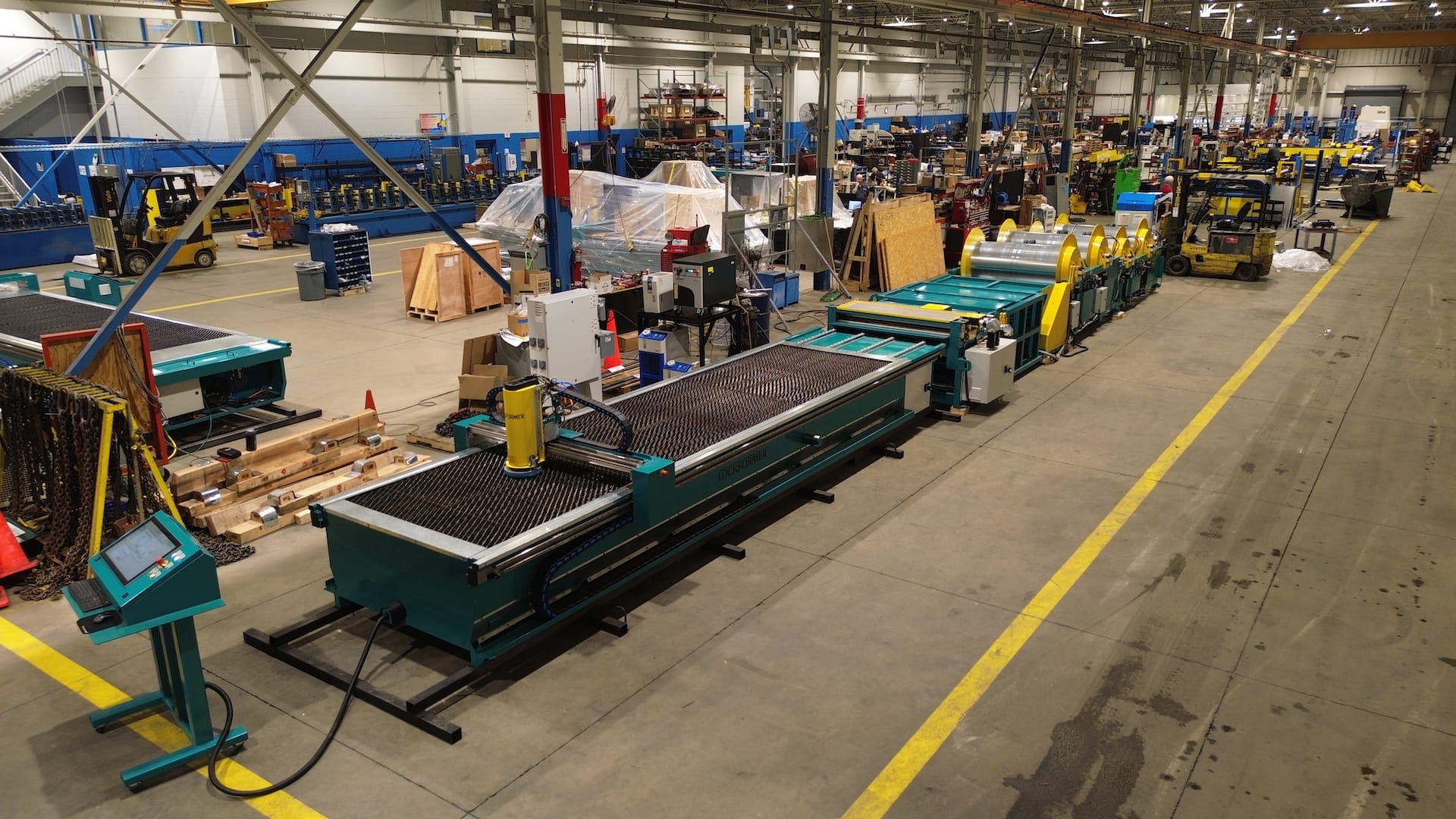 Large industrial workshop with conveyor belts and heavy machinery along a long, organized production line inside a factory.
