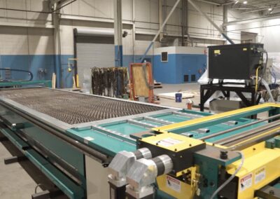 Industrial factory floor with a long green conveyor and a metal mesh belt, blue and gray walls in the background.